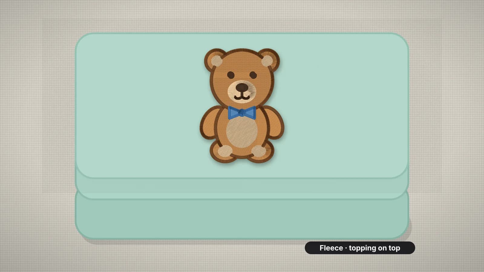 A folded mint fleece blanket with a teddy bear embroidered on it